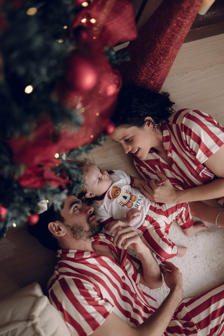 Pai e bebê deitados abraçados perto da árvore de Natal